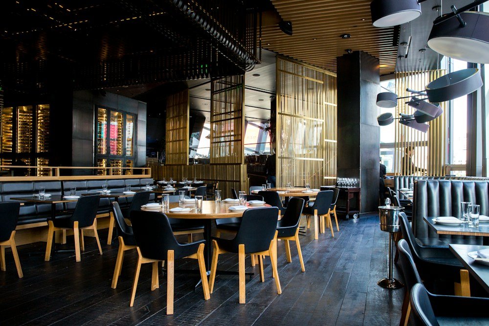 A warm restaurant filled with greenery and hanging lights
